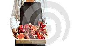 Girl holds wooden tray with fresh red vegetables and fruits on white background. Healthy eating vegetarian concept.