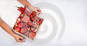 Girl holds wooden tray with fresh red vegetables and fruits on white background. Healthy eating vegetarian concept.