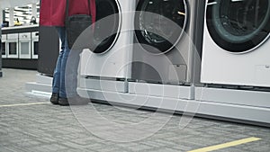 Girl in a home appliance shop buys a washing machine