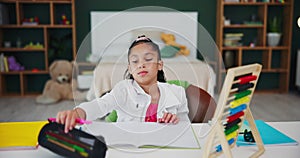 Girl, home and homework with book and pen in bedroom, child and student with abacus for counting or mathematics studying