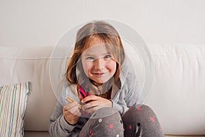 Girl at home sitting on sofa, eating breadsticks