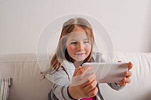 Girl at home sitting on sofa, taking selfie