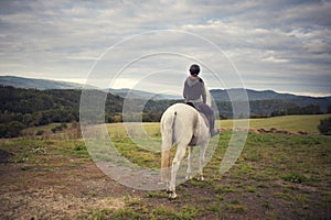 Girl with horse. The girl on a horse looks around the landscape. Horseback riding. Girl in the saddle