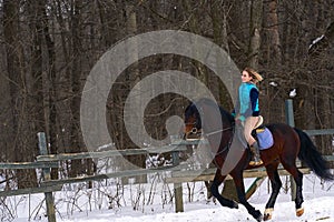 A girl on a horse jumps gallops. A girl trains riding a horse in a small paddock. A cloudy winter day