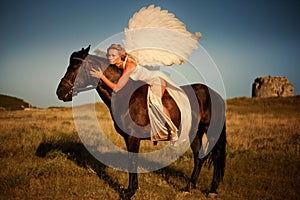 A girl on a horse with white angel wings at a horse