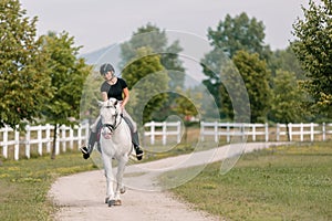 Girl, a horseback rider, riding snow white horse on a sunny day