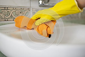 Girl hotel worker with cleaning products doing cleaning in the bathroom with a rag and a means for cleanlines