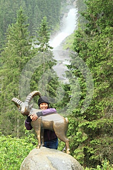 Girl hugging a chamois in front of waterfall