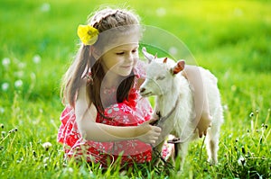 Girl hugging a goat in the garden on green grass