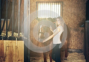 Girl hugging a horse in a stable at the ranch