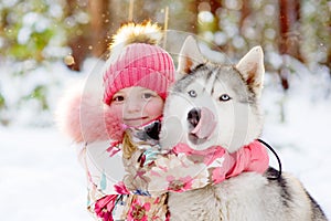Girl hugging Huskies in winter forest