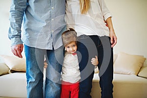 Girl hugging mom and dad for legs