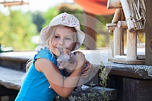 Girl hugging a pet cat, sphynx on veranda house