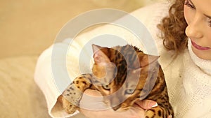 Girl hugging and playing with Bengal cat. Close-up.