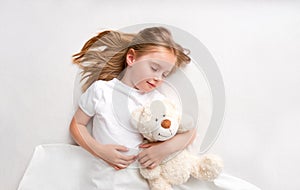 Girl hugging teddy bear laying on bed