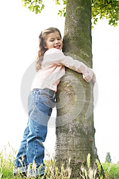 Girl hugging tree in park.