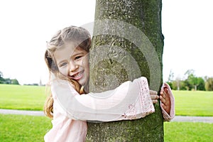 Girl hugging tree in park.