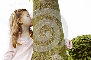 Girl hugging tree in park.