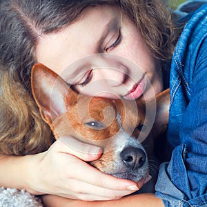 The girl hugs the basenji dog