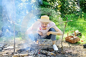 Girl hungry tourist can not wait when food will be roasted. Woman in straw hat try to bite sausage on stick. Girl eats