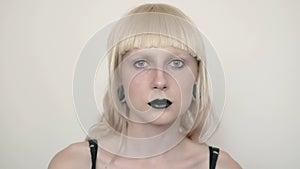 Girl in the image of albino with black lips and white eyes. Art beauty face. Picture taken in the studio on a white