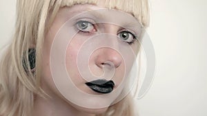 Girl in the image of albino with black lips and white eyes. Art beauty face. Picture taken in the studio on a white