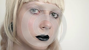 Girl in the image of albino with black lips and white eyes. Art beauty face. Picture taken in the studio on a white