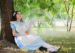 Girl in the image of the heroine of a fairy sitting under a tree