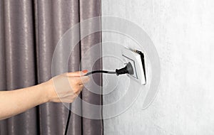 The girl incorrectly removes the electric plug from the socket and breaks the socket. Danger of electric shock, close-up