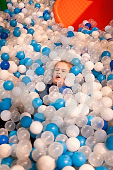 Girl at indoor amusement park among plastic balls.