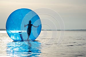 A girl in an inflatable attraction in the form of a ball on the sea