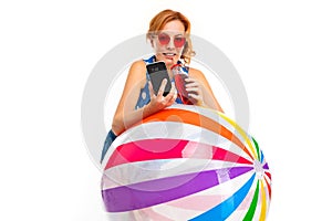 Girl with an inflatable ball for swimming, a phone and a glass of cocktail in her hands on a white background