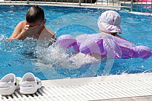 A girl with an inflatable circle and a boy play in the pool.