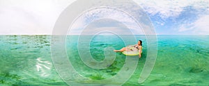 Girl in inflatable ring floating in the azure sea