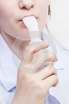 Girl inhales with mouthpiece of nebulizer close up