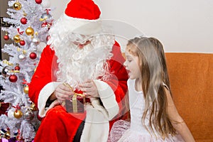 Girl with interest looks like Father Christmas helps to open her gift