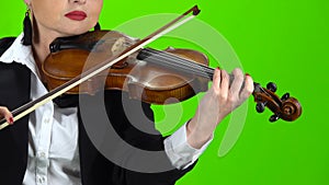 Girl in a jacket playing the violin. Green screen. Close up