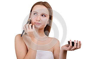 A girl with a jar of cream wants to apply it with a brush on her face on a white isolated background