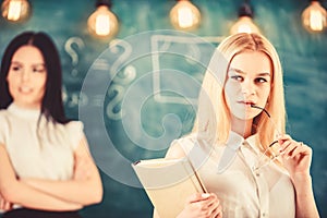 Girl jealous of success of classmate in classroom, chalkboard on background. Woman with book and eyeglasses looks dreamy