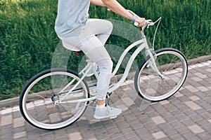 Girl in jeans and a T-shirt riding a blue bike on the city park