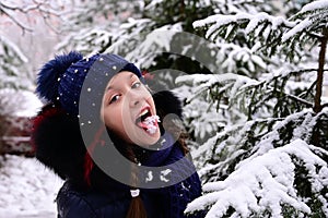 the girl jokingly eats snow in winter. Cheerful mood