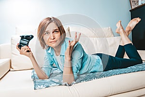 Girl with a joystick in her hands lies on the couch and plays a computer game. ESports concept