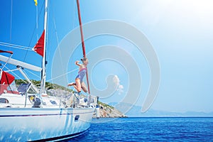 Girl jump in sea of sailing yacht on summer cruise. Travel adventure, yachting with child on vacation.