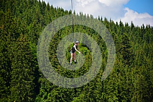 A girl jumped from a bungee jumping ride, hangs on a tight rope at a high altitude and smiles