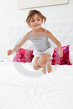 Girl Jumping On Bed Wearing Pajamas