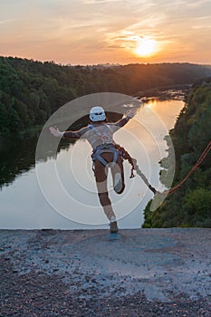 Girl jumping from the bridge. A girl with an incredible time is engaged in freestyle in bungee jumping. A young girl performs a