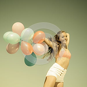 Girl jumping with colorful balloons on beach