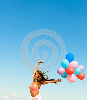 Girl jumping with colorful balloons on sky background