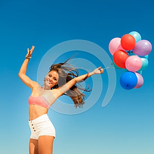 Girl jumping with colorful balloons on sky background
