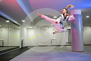 Girl jumping high in the air while practicing taekwondo